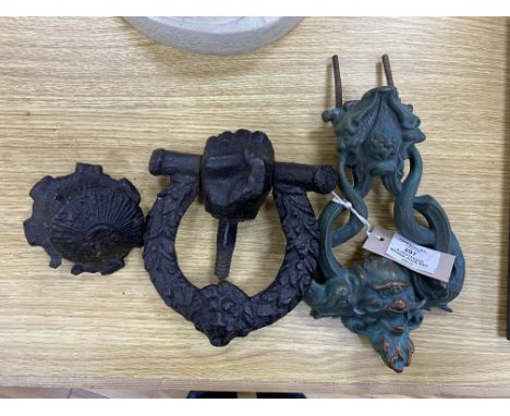 A grotesque bronze door knocker, 23 cm high and a similar cast-iron example