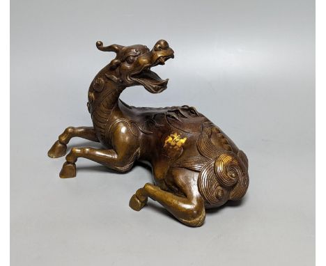 A Chinese parcel-gilt bronze incense burner and cover, modelled as a recumbent qilin, Qing dynasty, 19th century, 25 cms wide