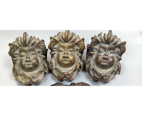 A set of three cast bronze mask-form furniture mounts, 9cm. high