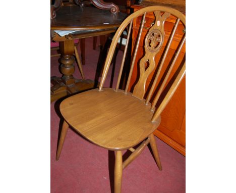 An Ercol dark elm extending dining table, having pull-out action and single fold-out leaf, together with two Ercol mid-elm st