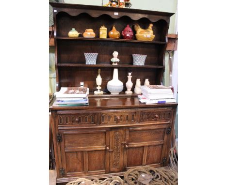 A dark wood dresser with three in-line drawers over two cupboard doors and three shelf plate rack