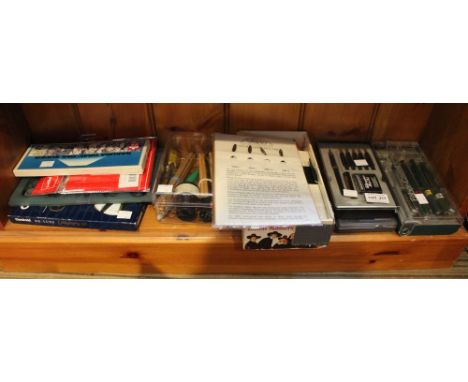 A shelf containing a selection of calligraphy pens accessories etc