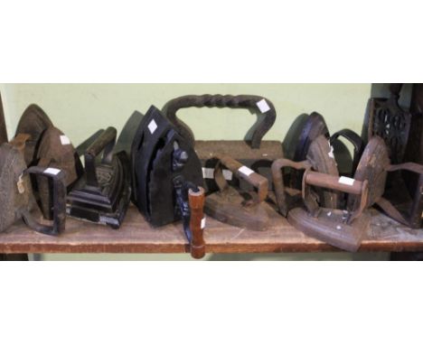 A shelf of vintage cast iron flat and smoothing irons