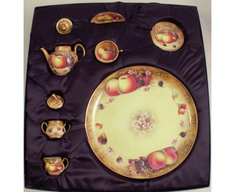 A Royal Worcester miniature tea service, each piece decorated with fruit to a mossy background by P Platt, comprising tea pot