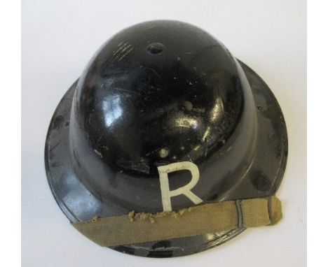 A WW2 metal helmet, painted black with a white "R" to each end