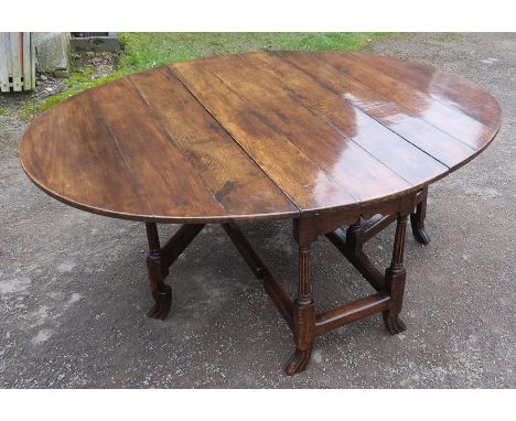 An oval oak gate leg dining table, raised on reeded legs, max length 56ins x 51ins x height 26.5ins