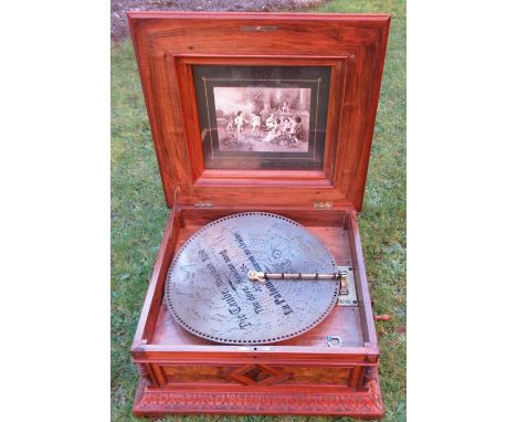 A Victorian walnut and inlaid table top polyphon, the lid inlaid with flowers and carved decoration, the inside of the lid wi