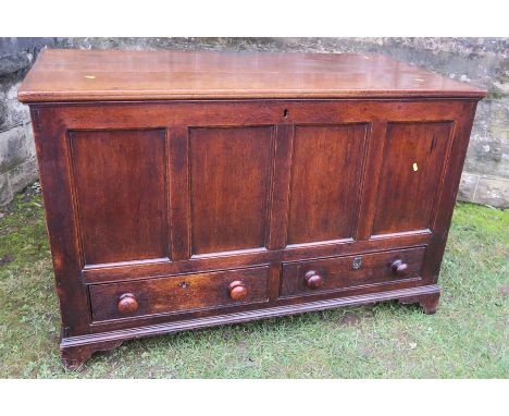 An 18th century oak mule chest, having four carved panels to the front and a plain rising lid, over two drawers, raised on br