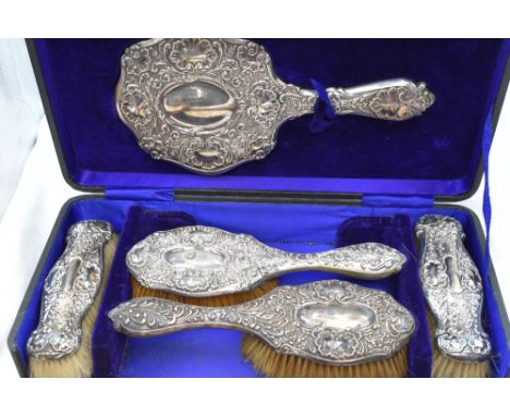 A cased Edwardian silver dressing table set (missing comb) having moulded scroll and flower decoration, Birmingham 1903, Will