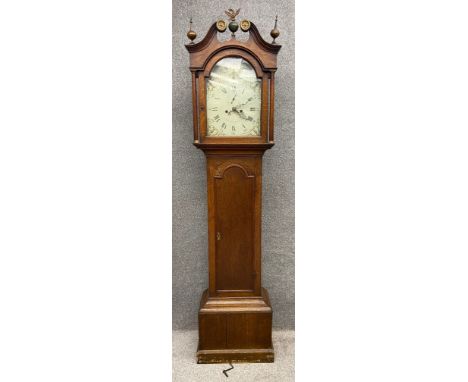 A 19th century oak long case clock on a moulded pedestal base below a long trunk door. With eight day movement and enamel and