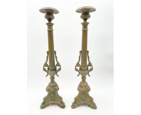 A pair of 19th century brass candlesticks with fluted stems flanked by grape and vine sprigs, on scrolling tripod supports wi