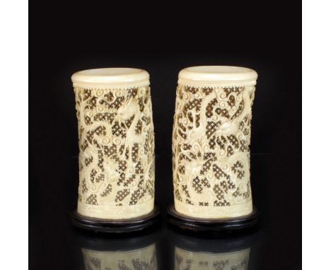 A pair of Canton reticulated ivory tusk vases, 19th Century, worked with wrythen dragons amid clouds on an openwork cellular 