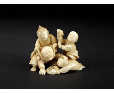 A Japanese ivory netsuke, Meiji period, modelled as a man at play with three boys, 4cm high.