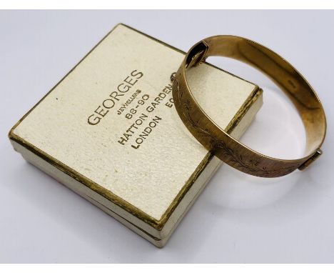 A 1960s 9ct gold hinged bangle with textured panels and foliate design. 26 grams approximately. with safty chain (chain a/f).
