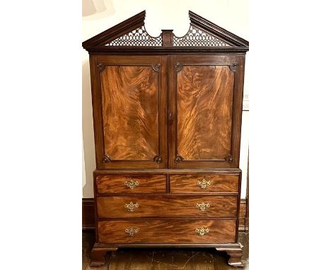 A George III mahogany linen press, in the style of Thomas  Chippendale, circa 1770, broken fretwork pediment on a dental corn