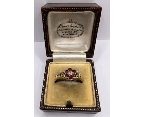 A late 19th century ruby and diamond daisy cluster ring, stamped 18ct. Approximate weight 3.3 grams, size O, in an antique Mo