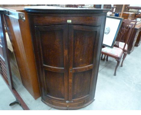 A George III oak bow fronted corner cupboard with base drawer. 55'' high