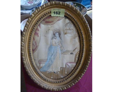 Textiles: A Regency period silk embroidered and watercolour picture, lady in an interior with caged bird. 8'' x 6'' oval