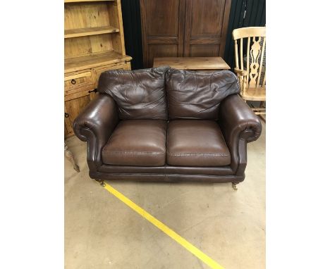 Two seater brown leather sofa on brass castors by Thomas Lloyd