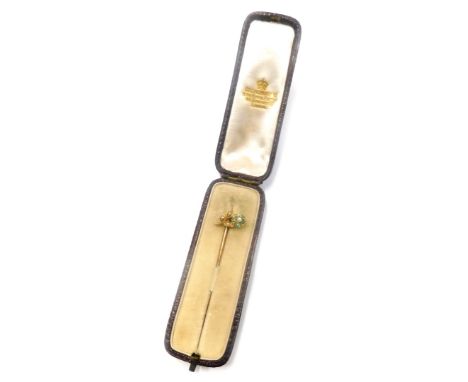 A stick pin, with floral design top set with seed pearl and turquoise, on a yellow metal backing, unmarked, on a yellow metal