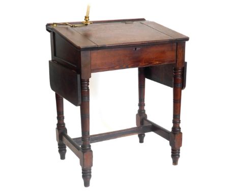 A Victorian pitch pine clerks desk, the sloped top with recess for inkwell and a adjustable candle stand, labels for George M