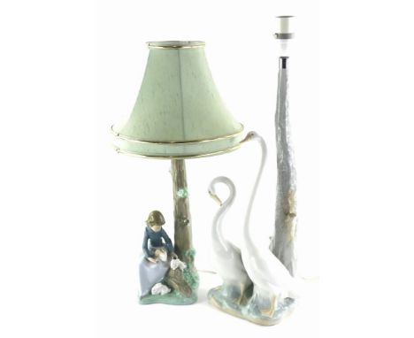 Two Nao porcelain table lamps, one depicting two geese, another a lady with rabbits.