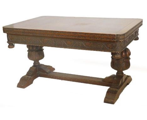 An early to mid 20thC oak draw leaf refectory table, the rectangular top with rounded corners above a frieze carved with grap