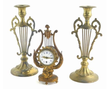 A late 19th/early 20thC gilt metal cased timepiece, of lyre form, with enamel dial, 24cm high, and a pair of gilt brass candl
