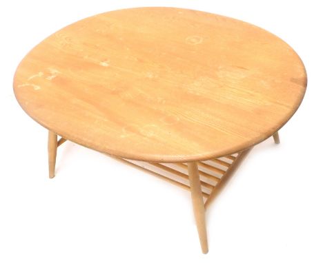 An Ercol oval light elm coffee table, with turned supports and magazine rack to under tier.