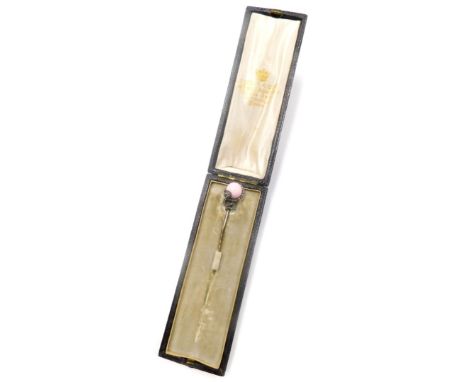 A stick pin, the top formed as a snake holding a pink orb, set with imitation tiny diamonds, on a gold coloured steel pin, in