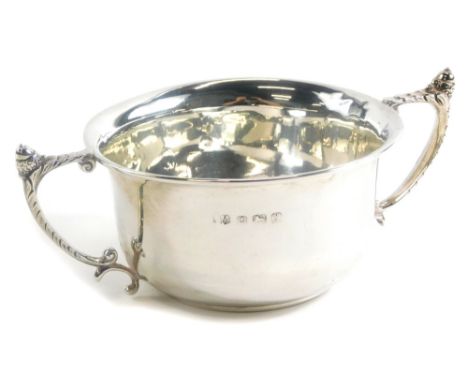 A George V silver two handled cup, of plain form with angular scroll handles each cast with an acorn finial, Birmingham 1922,