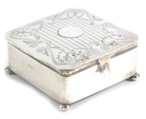 A George V silver jewellery or trinket box, of square form, the top with a shaped edge and a circular vacant cartouche and en