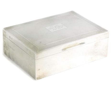 An Elizabeth II silver cigarette box, of rectangular form with engine turned decoration, the cartouche engraved with the insc