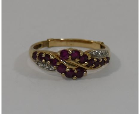 A 9 carat gold ruby and diamond cross over ring, the 14 small round mixed cut graduated rubies in claw setting, flanked eithe