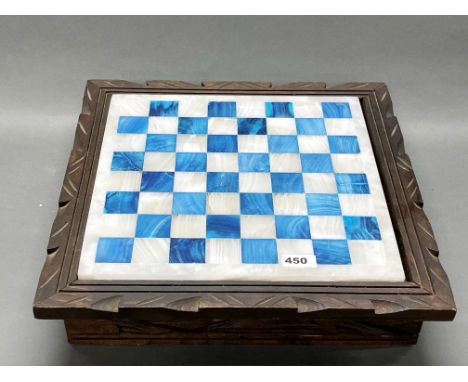 A polished onyx chess board inset into a wooden frame, 45 x 45cm, with an onyx chess set, king H. 11cm.