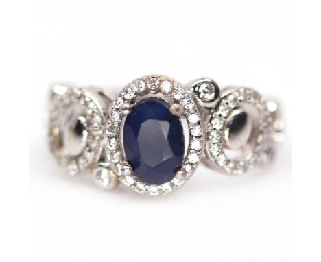 A 925 silver ring set with an oval cut sapphire and white stones, (K).