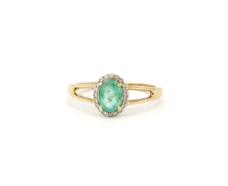 A hallmarked 9ct yellow gold (stamped 10K) ring set with an oval cut emerald surrounded by diamonds, (O).