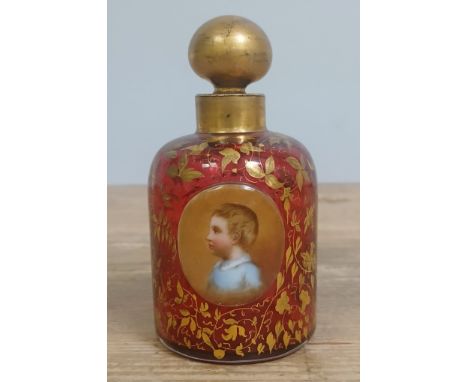 A 19th century Bohemian gilt ruby glass scent bottle with painted portrait depicting a young boy, height 11.5cm.&nbsp;In hous