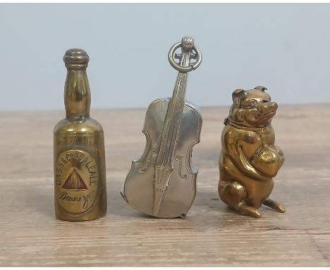 A group of three novelty vesta cases modelled as a Bass beer bottle, a cello and a pig.