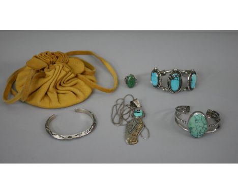 A collection of Native American turquoise jewellery with a yellow suede pouch. Including two silver bangles set with turquois