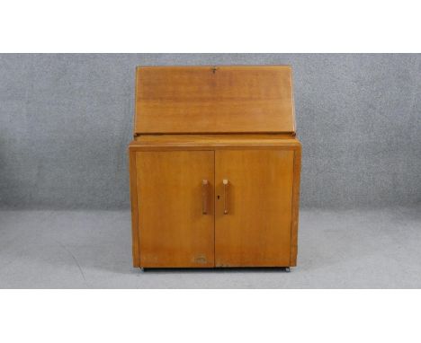 A mid century vintage light oak bureau with fitted interior above panel doors revealing drawers. H.95 W.110 D.54cm 