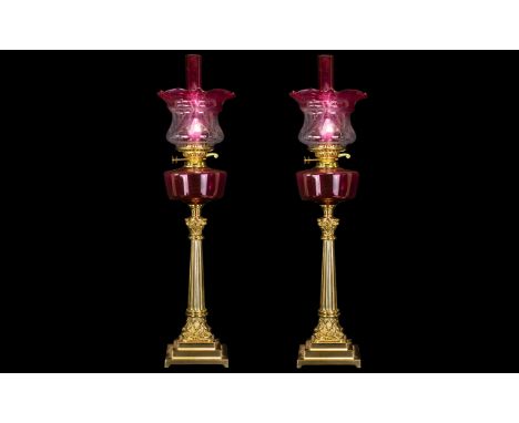 A Pair of Mid 20thC Oil Lamps with a ruby glass font and matching shade and funnel. Supported on a robust Corinthian column, 