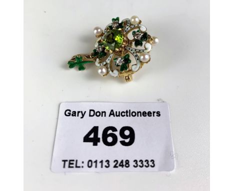 A peridot, pearl, diamond and enamel brooch ‘comprising a central faceted round mixed-cut peridot mounted within a raise yell