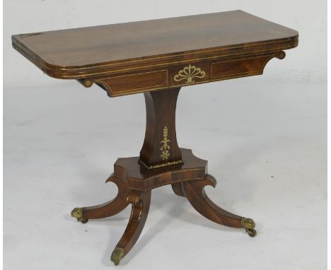 Regency rosewood and brass inlaid folding pedestal card table, circa 1820, the top inlaid with brass stringing and with anthe