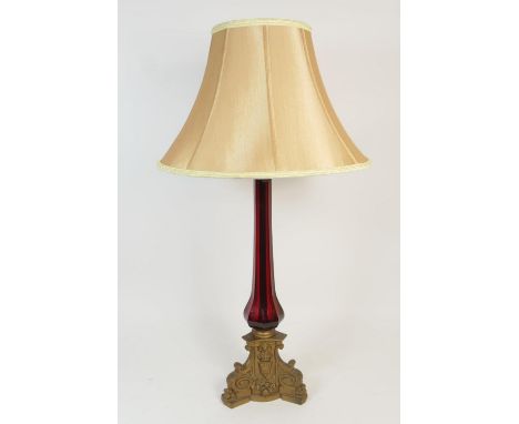 Victorian brass and ruby glass table lamp, having a brass capped octagonal ruby glass column over a cast brass triform base, 