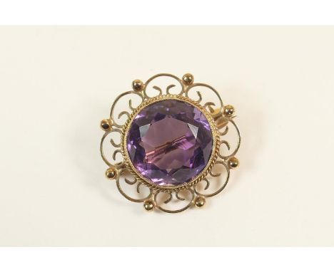 Amethyst circular brooch, the central stone approx. 15mm diameter, within a 9ct gold wirework setting, 25mm, gross weight app