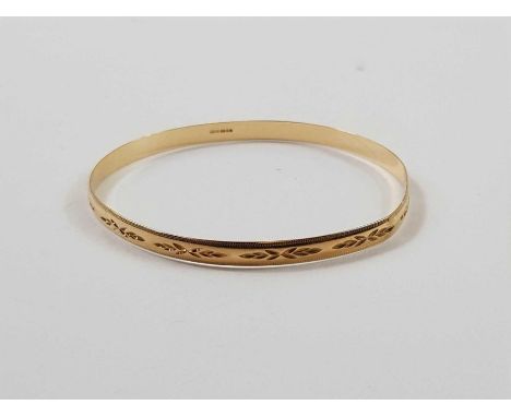 A 9ct gold solid bangle, engraved decoration throughout, 5mm wide, 7.44 grams gross