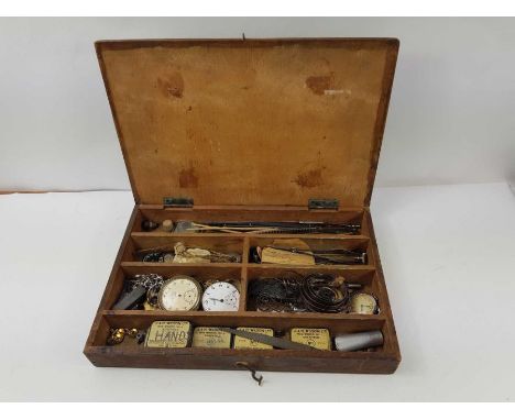 A wooden case containing vintage watch parts to include dials, hands, springs and other items