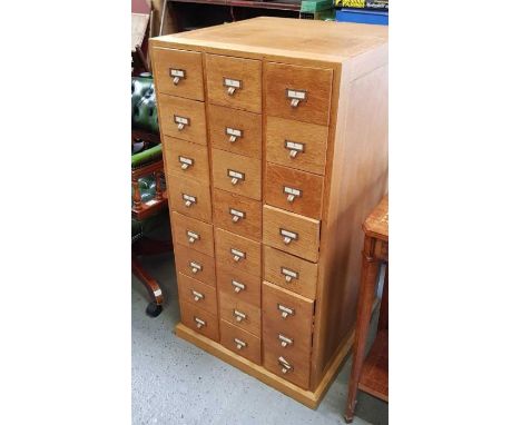 A light oak filing cabinet of 24 small drawers arranged in three rows, 117cms high 60cms wide 60cms deep