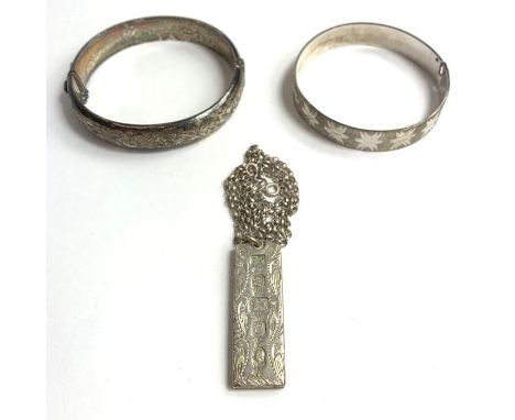 A silver bangle, with satin finish and bright cut decoration; a silver half engraved hinged bangle; and a silver ingot with e